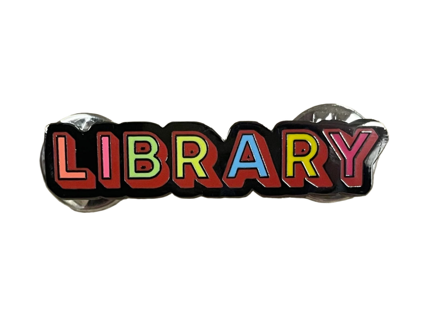 front of enamel pin that says library in rainbow letters on a black background