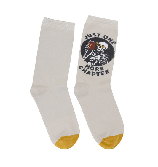 White socks with a skeleton reading and text 'Just One More Chapter' on a white background